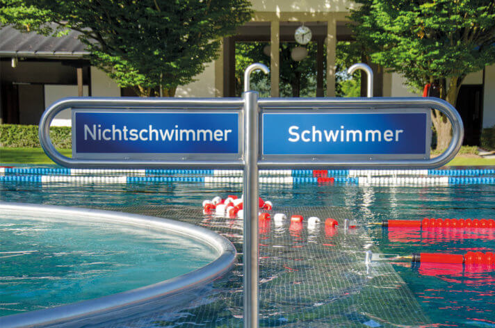 Trennungsschild: Nichtschwimmer und Schwimmer. Im Hintergrund ist das Becken zu sehen.