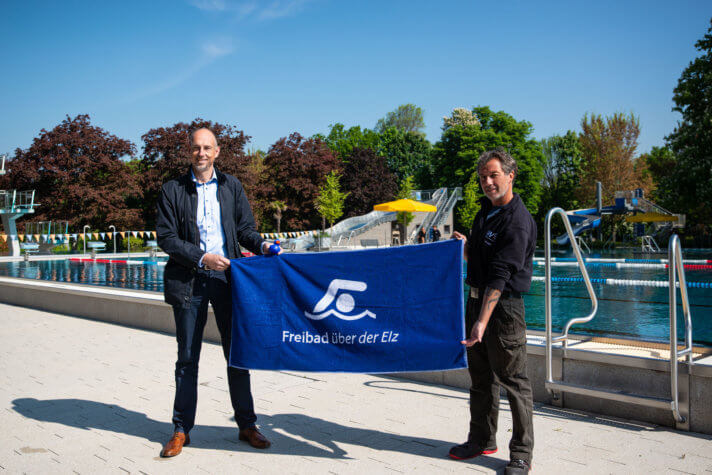 Stadtwerke Chef Björn Michel und Schwimmmeister Jörg Staiger präsentieren das neue Freibad Badetuch im Freibad über der Elz