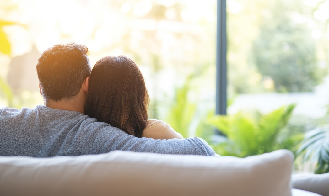 Mann und Frau sitzen auf dem Sofa und schauen aus dem Fenster